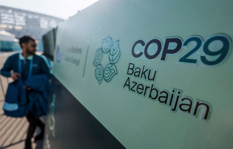 © Reuters. A man walks past a logo of the COP29 United Nations climate change conference, in Baku, Azerbaijan November 22, 2024. REUTERS/Maxim Shemetov