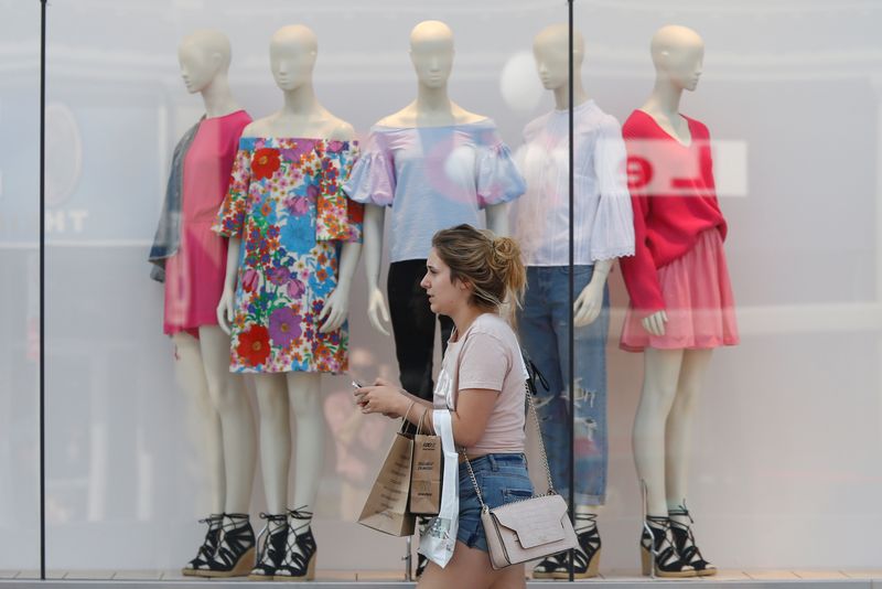 © Reuters. FILE PHOTO: A woman carries shopping bags while walking past a window display outside a retail store in Ottawa, Ontario, Canada, July 21, 2017. REUTERS/Chris Wattie/File photo