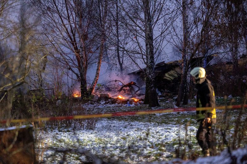 © Reuters. FILE PHOTO: Rescuer walks past DHL cargo plane wreckage, at the crash site near Vilnius International Airport, Lithuania November 25, 2024. Lukas Balandis/BNS via REUTERS/File Photo