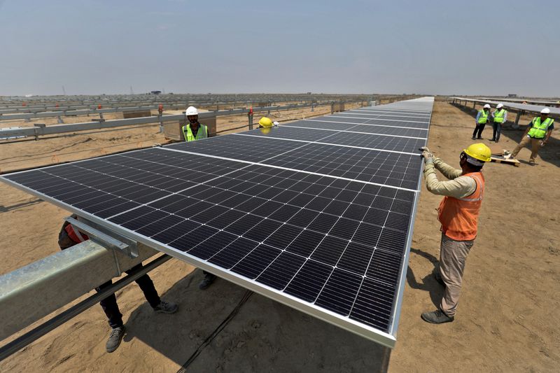 © Reuters. FILE PHOTO: Workers install solar panels at the Khavda Renewable Energy Park of Adani Green Energy Ltd (AGEL)  in Khavda, India, April 12, 2024.REUTERS/Amit Dave/File Photo