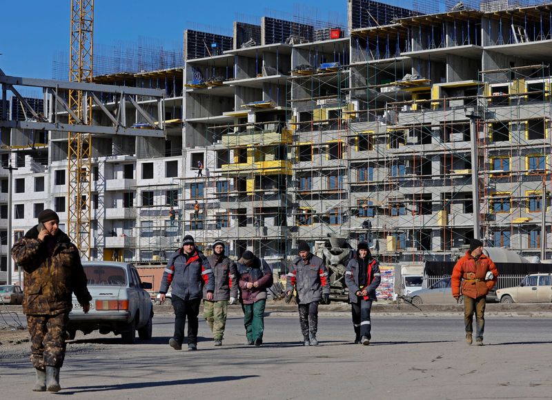 © Reuters. FILE PHOTO: Workers walk in front of an apartment building under construction, in the course of Russia-Ukraine conflict in Mariupol, Russian-controlled Ukraine, February 10, 2023. REUTERS/Alexander Ermochenko/File Photo