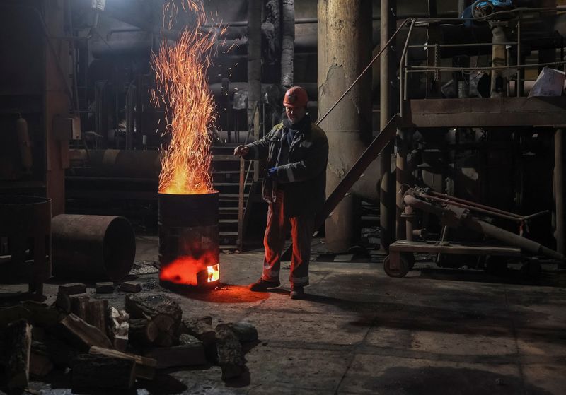 © Reuters. A worker warms himself near a wood stove as he fixes a thermal power plant damaged by a Russian missile strike, amid Russia's attack on Ukraine, at an undisclosed location in Ukraine November 28, 2024. REUTERS/Gleb Garanich