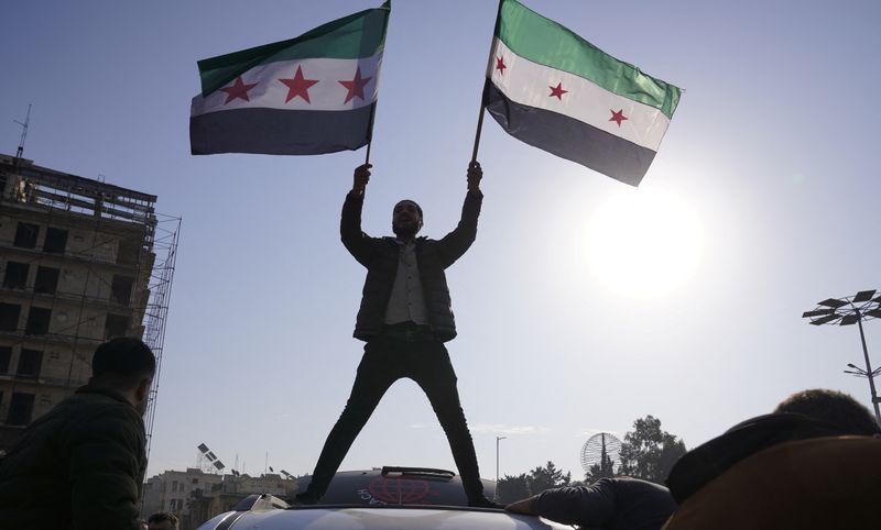 © Reuters. A man holds the Syrian opposition flag as they celebrate after Syria's army command notified officers on Sunday that President Bashar al-Assad's 24-year authoritarian rule has ended, a Syrian officer who was informed of the move told Reuters, following a rapid rebel offensive that took the world by surprise, in Aleppo, Syria December 8, 2024. REUTERS/Karam al-Masri