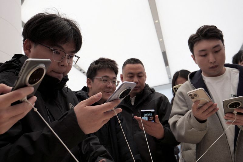 © Reuters. FILE PHOTO: Visitors look at Huawei's newly unveiled Mate 70 smartphone series at a flagship store in Beijing, China November 26, 2024.  REUTERS/Xiaoyu Yin/File Photo