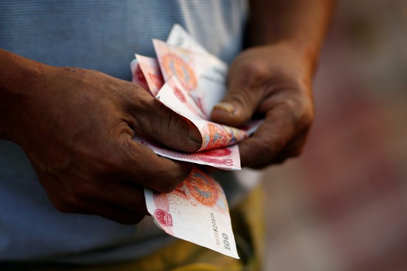 © Reuters. FILE PHOTO: A man counts money as he poses for a picture in Beijing, China, September 21, 2016.   REUTERS/Thomas Peter/File Photo