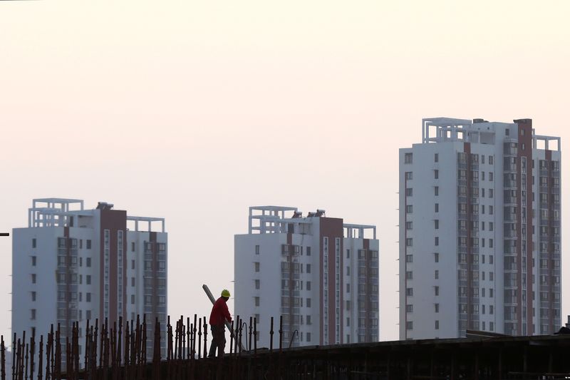 © Reuters. FILE PHOTO: A worker stands on the scaffolding at a construction site against a backdrop of residential buildings in Huaian, Jiangsu province, China October 18, 2018. Picture taken October 18, 2018.  REUTERS/Stringer/File Photo