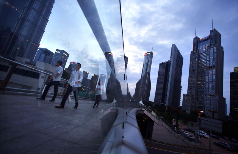 © Reuters. FILE PHOTO: People cross a bridge at Pudong financial district in Shanghai August 11, 2014. REUTERS/Carlos Barria/File Photo