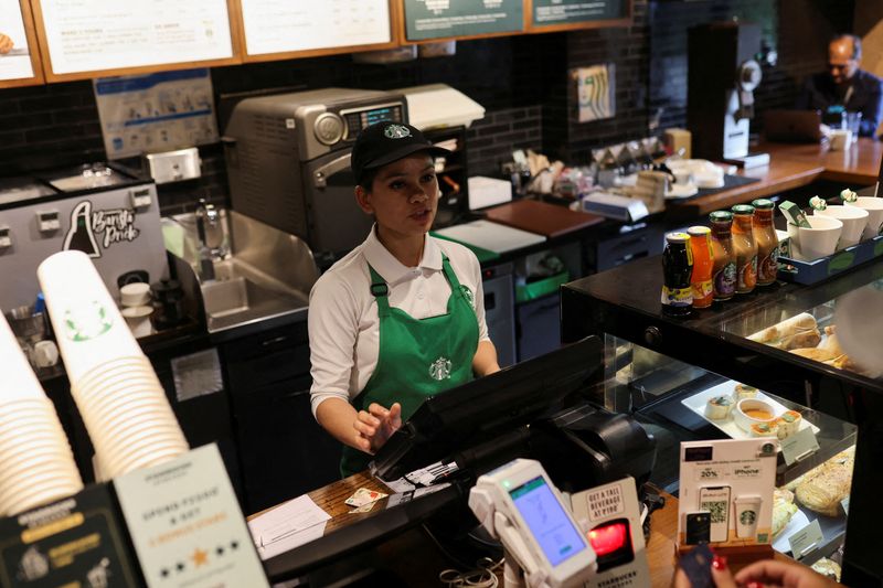 © Reuters. FILE PHOTO: An employee takes a customer's order at a Starbucks' outlet at a market in New Delhi, India, May 30, 2023. REUTERS/Anushree Fadnavis/File Photo