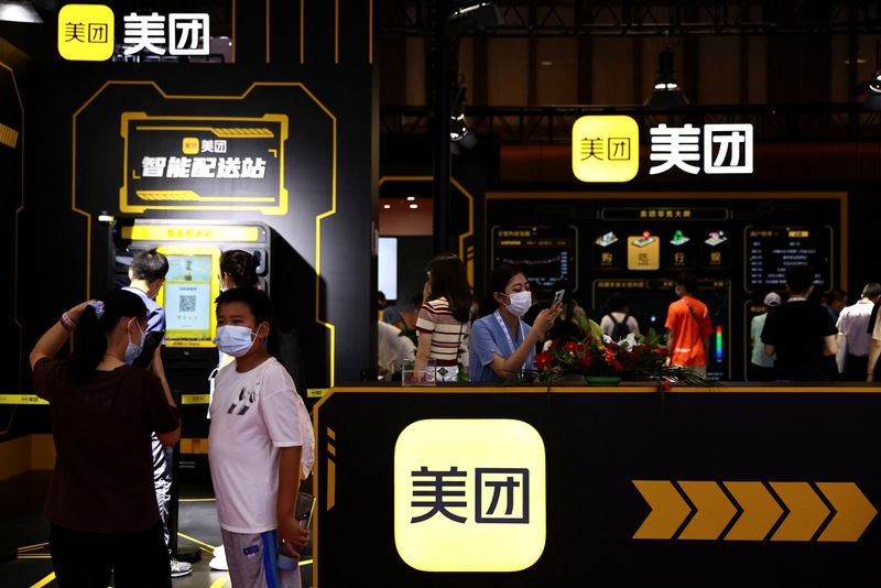 © Reuters. FILE PHOTO: Visitors stand near a booth of Meituan at the 2022 World Robot Conference in Beijing, China August 18, 2022. REUTERS/Tingshu Wang/File Photo