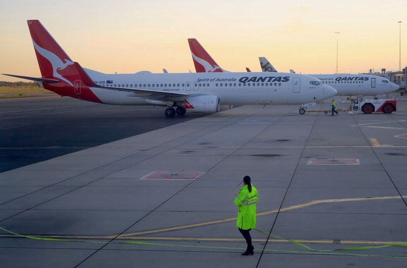 © Reuters. FILE PHOTO: Workers can be seen near Qantas Airways, Australia's national carrier, Boeing 737-800 aircraft on the tarmac at Adelaide Airport, Australia, August 22, 2018. REUTERS/David Gray/File Photo