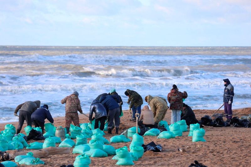 © Reuters. Volunteers work to clean up spilled oil on the shoreline following an incident involving two tankers damaged in a storm in the Kerch Strait, during an emergency response operation in the Black Sea resort of Anapa, Russia, in this picture released December 18, 2024. Anapa Mayor's Office/Handout via REUTERS