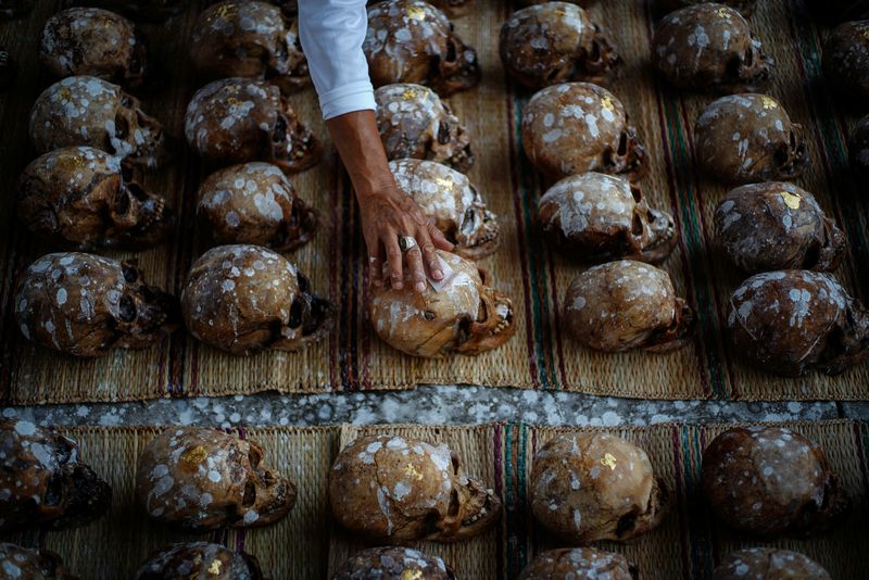 © Reuters. A volunteer places a gold leaf on a human skull during a Lang Pa Cha mass cleansing ceremony for unclaimed bodies, at the Sawang Metta Thammasathan Foundation in Nakhon Ratchasima province, Thailand, June 1, 2024. As the day of cremation draws near, the volunteers use toothbrushes and holy water to gently wash the mud from the remains, before adorning them with gold leaf. The decorated remains are then arranged in two separate pyres - one for men and one for women.       REUTERS/Athit Perawongmetha