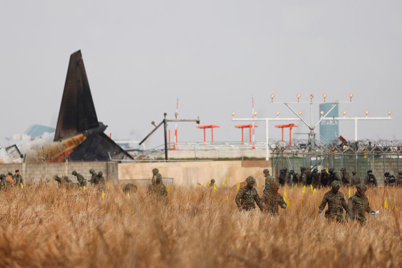 © Reuters. Military personnel work at the site where an aircraft went off the runway and crashed at Muan International Airport, in Muan, South Korea, December 30, 2024. REUTERS/Kim Soo-hyeon