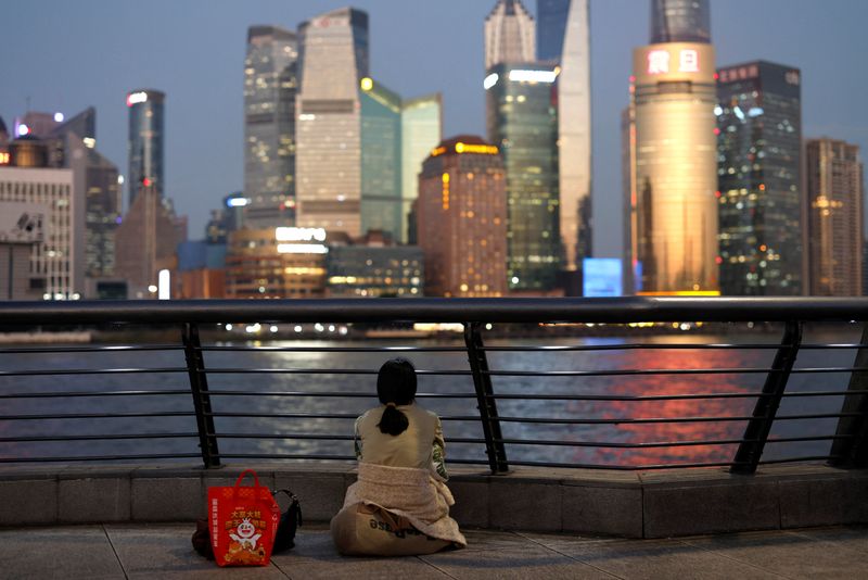 © Reuters. FILE PHOTO: A woman sits on the Bund near Huangpu river as she looks on the financial district of Pudong in Shanghai, China September 27, 2024. REUTERS/Tingshu Wang/File Photo