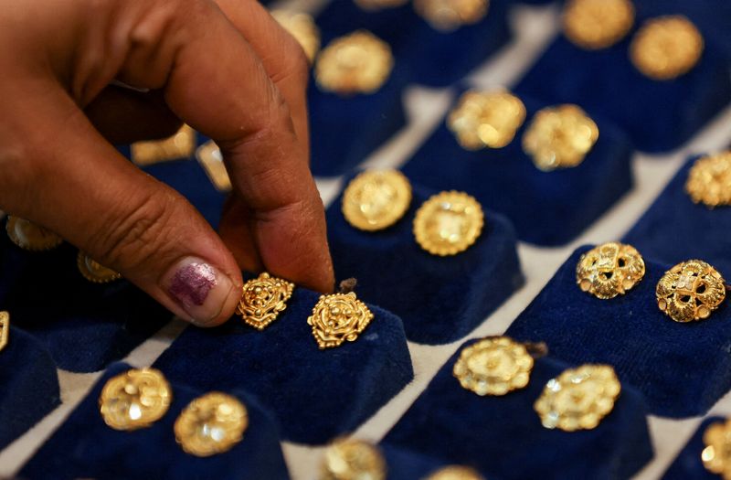 © Reuters. FILE PHOTO: A woman picks a gold earring at a jewellery shop in the old quarters of Delhi, India, May 24, 2023. REUTERS/Anushree Fadnavis/File Photo