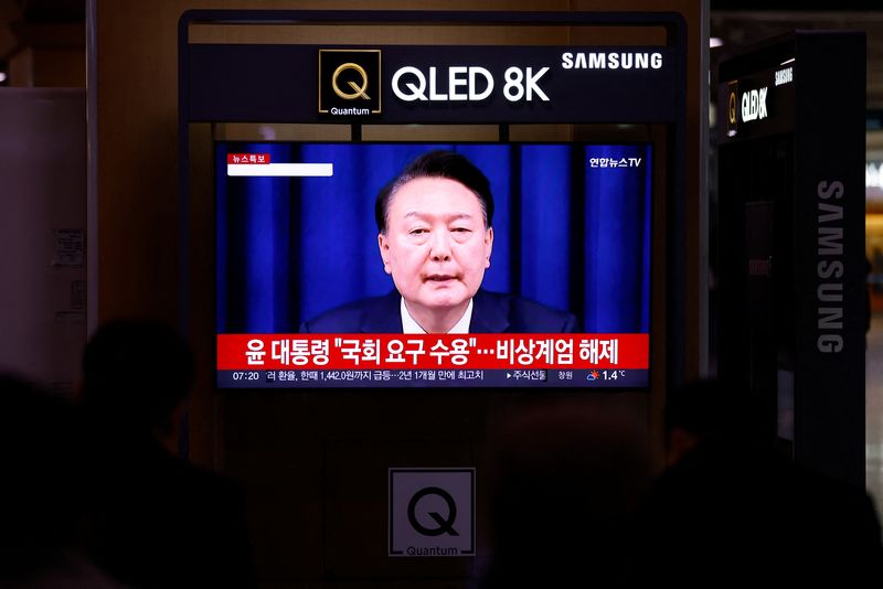 © Reuters. FILE PHOTO: People watch a TV screen broadcasting a news report on South Korean President Yoon Suk Yeol's declaration of martial law and the following announcement that he will lift the martial law, after parliamentary vote, at a railway station in Seoul, South Korea, December 4, 2024. REUTERS/Kim Soo-hyeon/File Photo