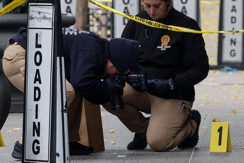 © Reuters. FILE PHOTO: A member of the NYPD Crime Scene Unit takes a picture of a shell casing found at the scene where the CEO of UnitedHealthcare Brian Thompson was reportedly shot and killed in Midtown Manhattan, in New York City, U.S., December 4, 2024. REUTERS/Shannon Stapleton/File Photo