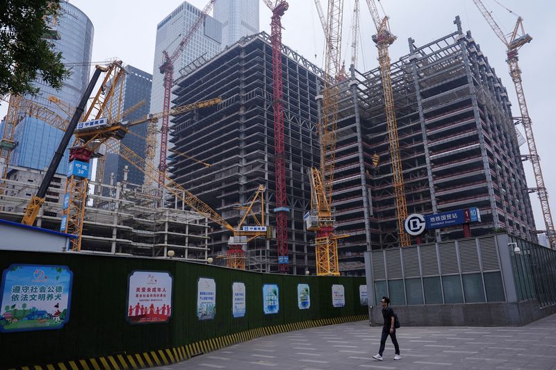 © Reuters. FILE PHOTO: A person walks past a construction site in Beijing's Central Business District (CBD), China July 14, 2024. REUTERS/Tingshu Wang/File Photo