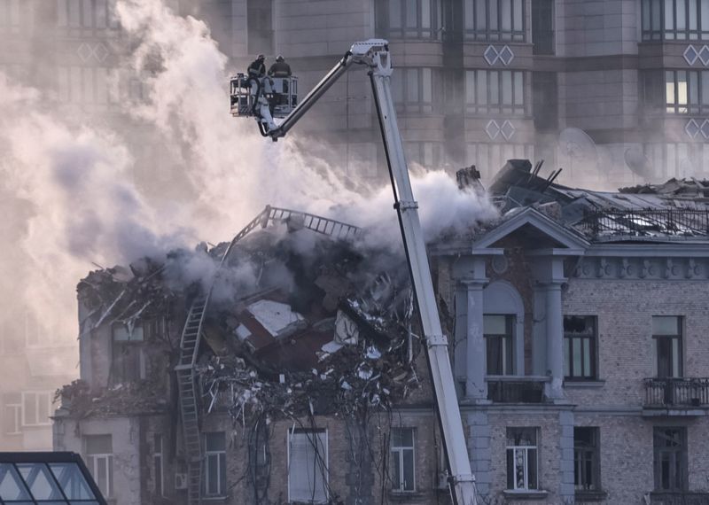 © Reuters. Firefighters work at a site of a building damaged during a Russian drone strike, amid Russia's attack on Ukraine, in central Kyiv, Ukraine January 1, 2025. REUTERS/Yan Dobronosov