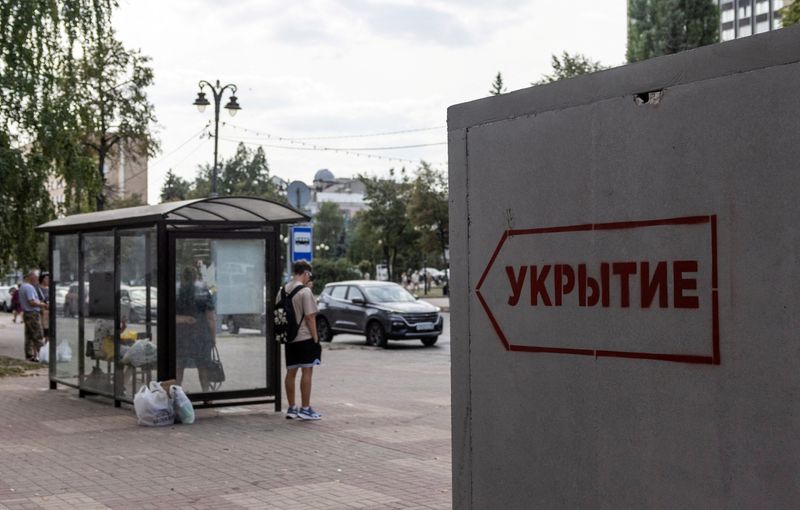 © Reuters. FILE PHOTO: People wait at a bus stop next to a reinforced concrete bomb shelter installed in a street in the course of Russia-Ukraine conflict, in Kursk, Russia August 28, 2024. The sign on the construction reads: