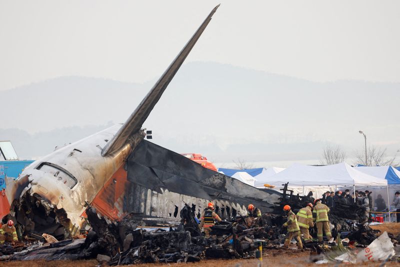 © Reuters. FILE PHOTO: People work at the site where an aircraft went off the runway and crashed at Muan International Airport, in Muan, South Korea, December 30, 2024. REUTERS/Kim Soo-hyeon/File Photo