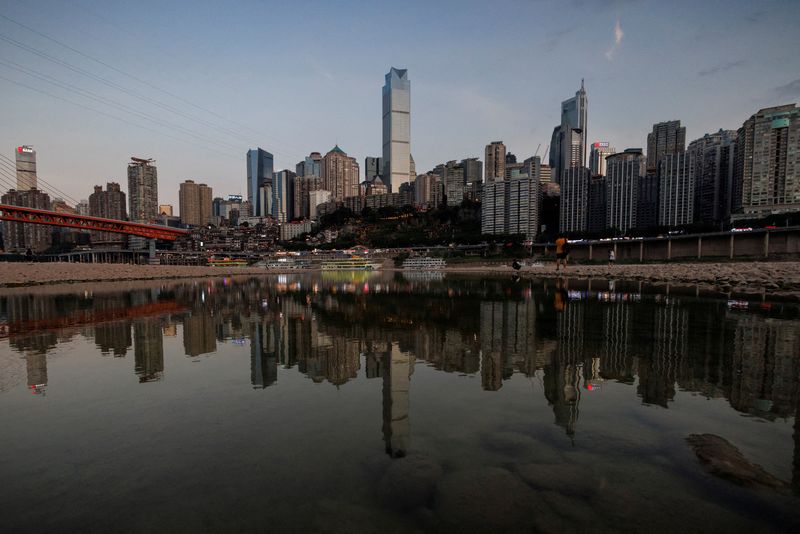 © Reuters. FILE PHOTO: The city skyline is reflected in a pool left on the dry riverbed of the receding Jialing river, a tributary of the Yangtze, that is approaching record-low water levels during a regional drought in Chongqing, China, August 20, 2022. REUTERS/Thomas Peter/File Photo