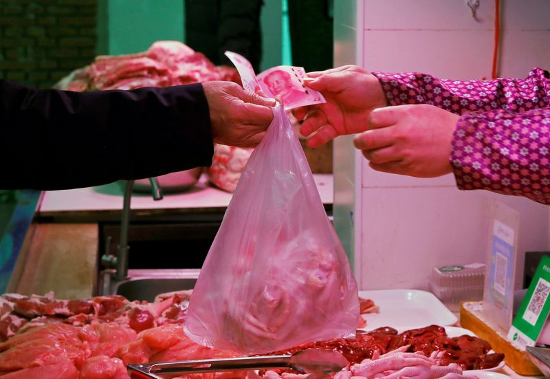 © Reuters. FILE PHOTO: A man pays for meat at a market in Beijing, China January 11, 2021. REUTERS/Tingshu Wang/ File Photo