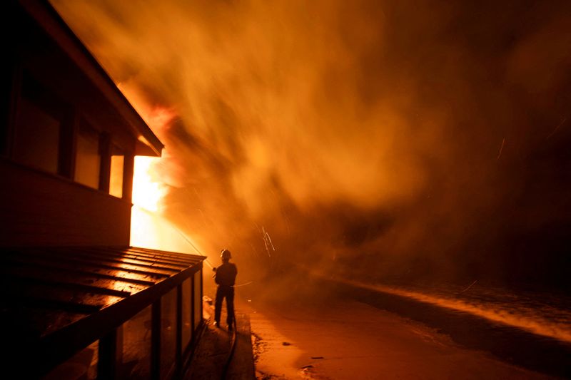 © Reuters. FILE PHOTO: A firefighter battles the Palisades fire as it burns during a windstorm on the west side of Los Angeles, California, U.S. January 8, 2025. REUTERS/Ringo Chiu/File photo