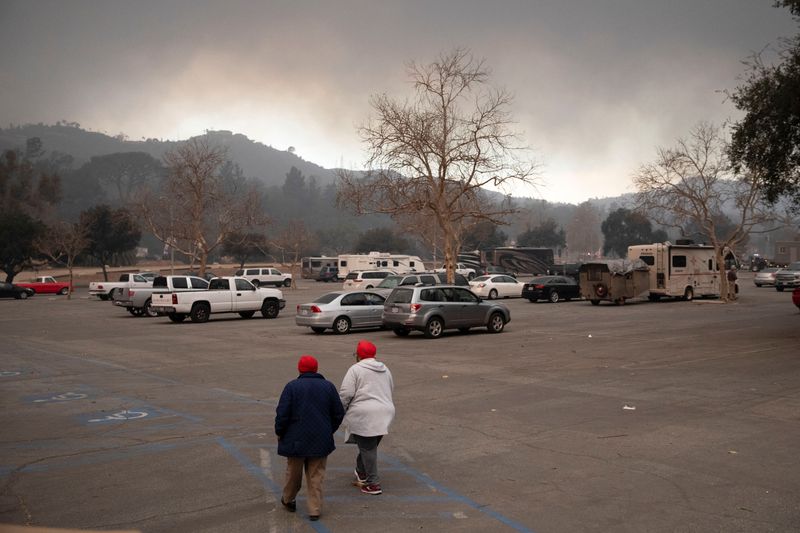 © Reuters. Dorthy Brown and her daughter walk through the parking lot of the Rose Bowl, as powerful winds fueling devastating wildfires in Los Angeles area forced people to evacuate, in Pasadena, California, U.S. January 8, 2025. REUTERS/Zaydee Sanchez