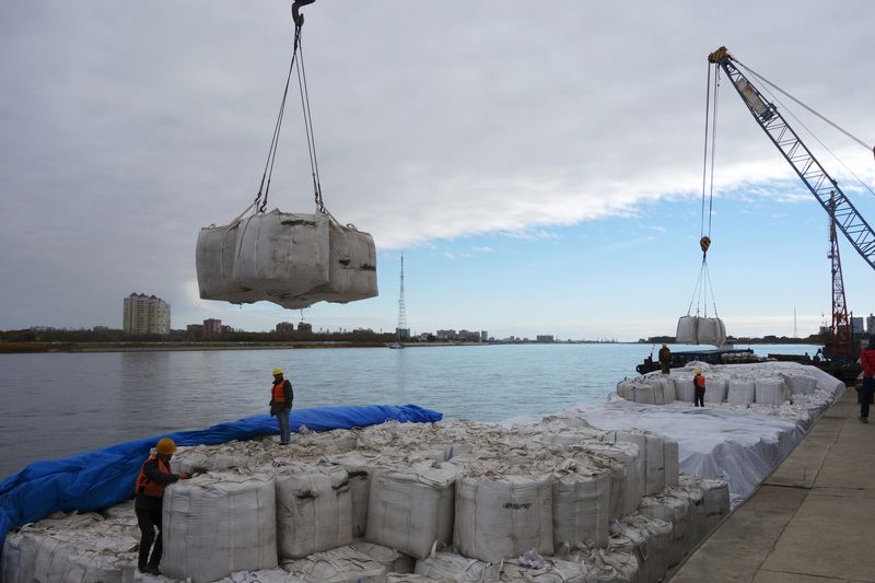 © Reuters. FILE PHOTO: Workers stand near a crane unloading sacks of imported soybeans from Russia at Heihe port in Heilongjiang province, China October 10, 2018. REUTERS/Stringer/File Photo