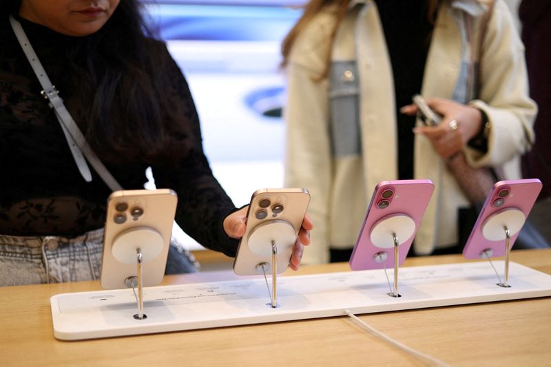 © Reuters. FILE PHOTO: Women use Apple iPhone smartphones displayed at a store in London, Britain, October 6, 2024. REUTERS/Hollie Adams/File Photo