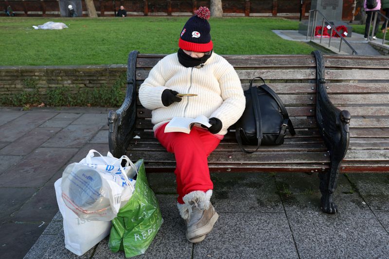 © Reuters. FILE PHOTO: A person wearing winter clothes sits on a bench with shopping bags in the cold weather in London, Britain, January 11, 2025.  REUTERS/Kevin Coombs/File Photo