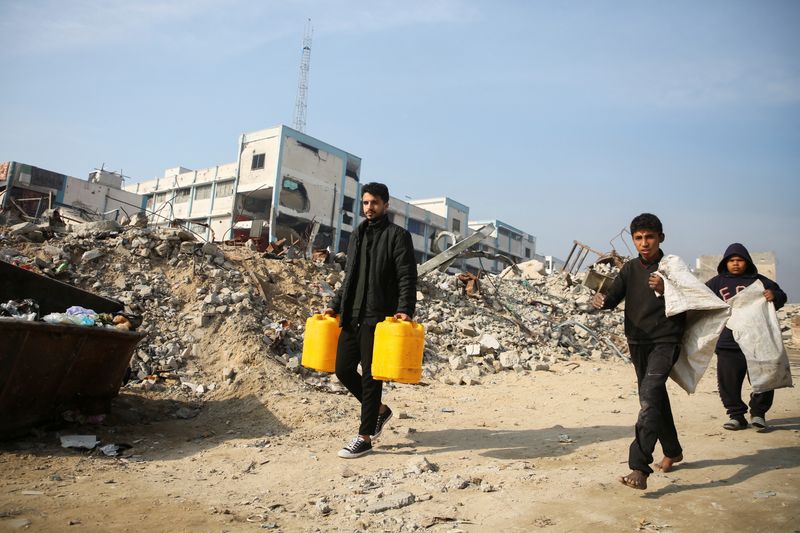 © Reuters. Palestinians walk past the rubble of buildings destroyed in previous Israeli strikes, ahead of a ceasefire set to take effect on Sunday, in Khan Younis in the southern Gaza Strip January 16, 2025. REUTERS/Hatem Khaled