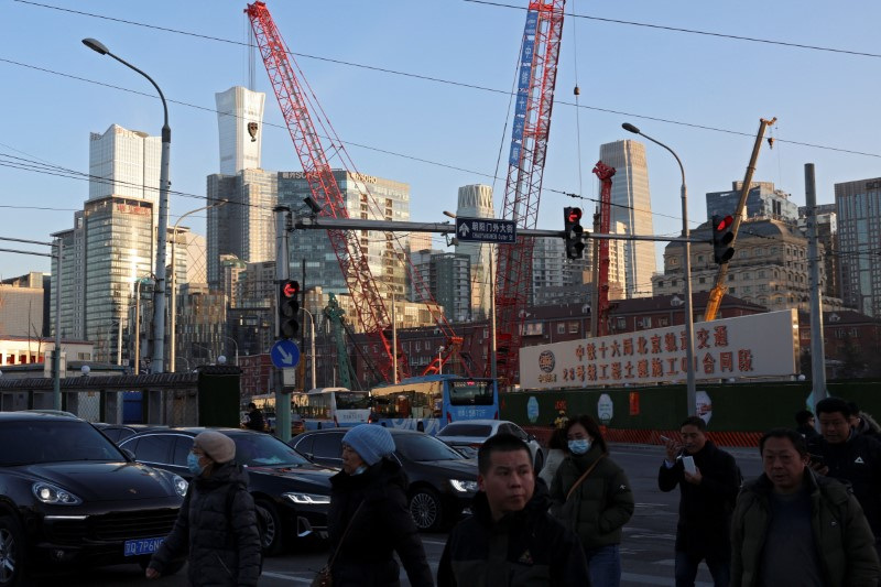 © Reuters. People cross an intersection near cranes standing at a construction site in Beijing, China January 15, 2024. REUTERS/Florence Lo