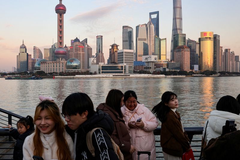 © Reuters. People hang out at The Bund as the financial district of Pudong is seen in the background in Shanghai, China, January 16, 2025.  REUTERS/Go Nakamura