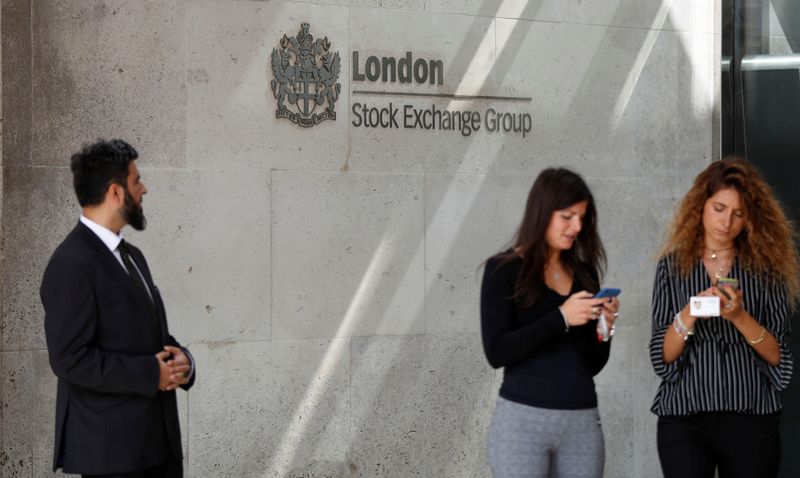 © Reuters. FILE PHOTO: People check their mobile phones as they stand outside the entrance of the London Stock Exchange in London, Britain. Aug 23, 2018. REUTERS/Peter Nicholls/File Photo