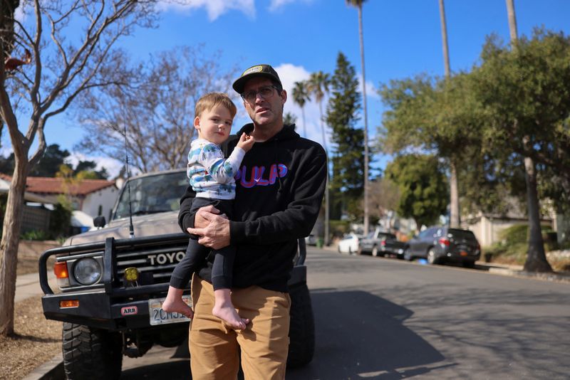 © Reuters. John Adolf holds his son Remey, as he stays with his friends after his home in Altadena was damaged during the Eaton Fire, in Eagle Rock, California, U.S., January 17, 2025. REUTERS/David Swanson