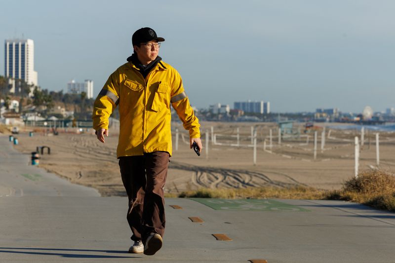 © Reuters. Alex Choi, who loves documenting situations for social media and says millions of people have viewed his video of the Palisades Fire on Snap Chat and Instagram, walks along an empty beach near the Palisades Fire, in  Los Angeles  California, U.S. January 19, 2025.  REUTERS/Mike Blake