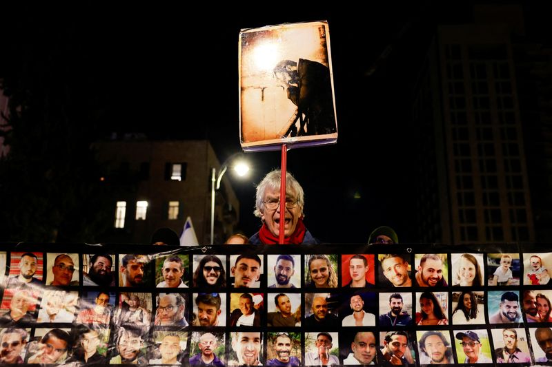 © Reuters. A man holds a placard as families and supporters of the Israeli hostages kidnapped during the deadly October 7 2023 attack by Hamas attend a demonstration in support of ceasefire deal between Israel and Hamas, the day before it goes into effect, in Jerusalem, January 18, 2025. REUTERS/Ammar Awad     TPX IMAGES OF THE DAY