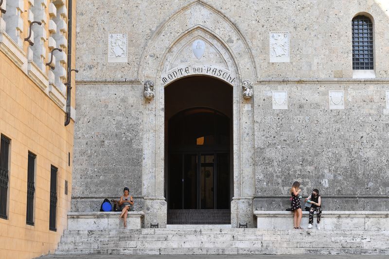 © Reuters. FILE PHOTO: People stand at the entrance of the headquarters of Monte dei Paschi di Siena (MPS) in Siena, Italy, August 11, 2021. REUTERS/Jennifer Lorenzini/File Photo