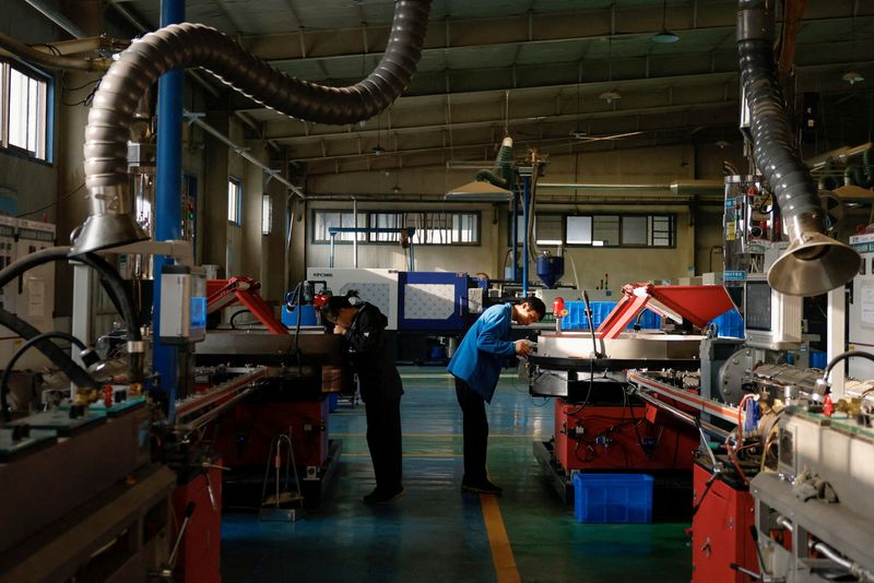 © Reuters. FILE PHOTO: Workers monitor the production line of drip tape fittings at a factory of DAYU Water Group Co, in Jiuquan, during an organised media tour in Gansu province, China October 18, 2024. REUTERS/Tingshu Wang/File Photo