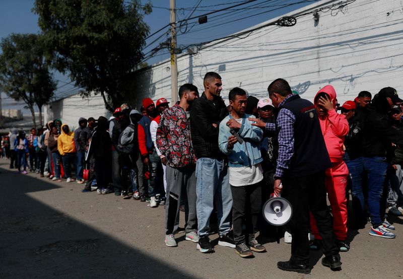 © Reuters. An official of the Commission for Refugee Assistance (COMAR) talks with migrants outside the Mexican Commission for Refugee Assistance (COMAR), as they wait in line to regularise their migratory situation in the country, in Mexico City, Mexico January 24, 2025. REUTERS/Henry Romero