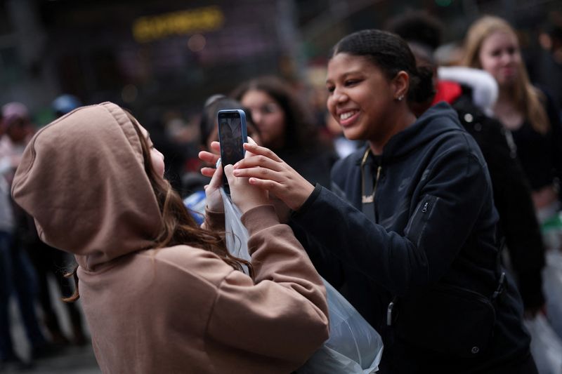 © Reuters. FILE PHOTO: A young woman makes a video of her friends with a mobile phone to post on TikTok in Times Square in New York City, New York, U.S., March 13, 2024. REUTERS/Mike Segar/File photo