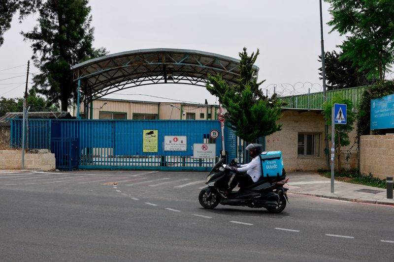 © Reuters. FILE PHOTO: A man drives a scooter past the UNRWA headquarters, in Jerusalem, May 10, 2024. REUTERS/Ammar Awad/File Photo