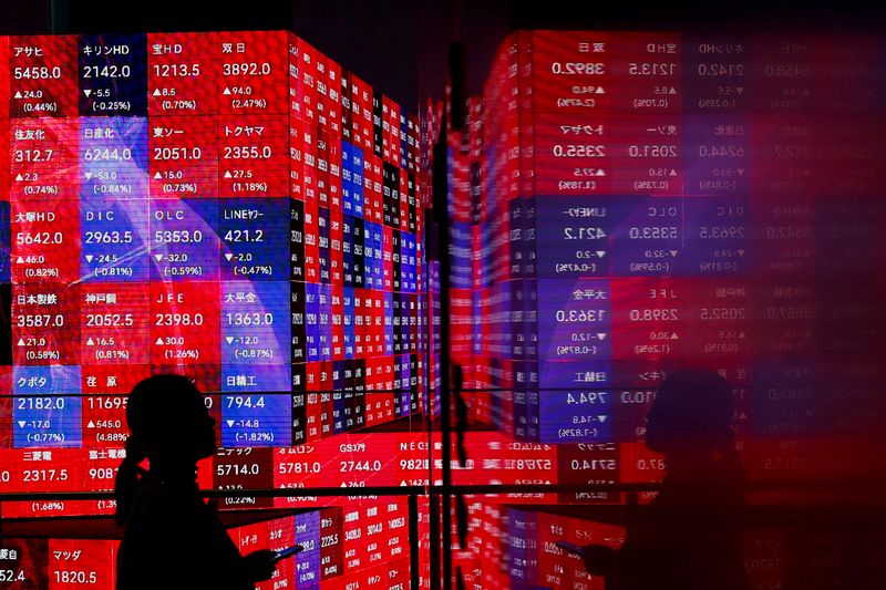 © Reuters. A visitor stands next to an electronic screen displaying Japan's Nikkei stock prices quotation board, inside a building in Tokyo, Japan February 22, 2024.  REUTERS/Issei Kato/File Photo