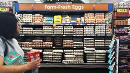 A supermarket shopper walks past a display of eggs for sale.